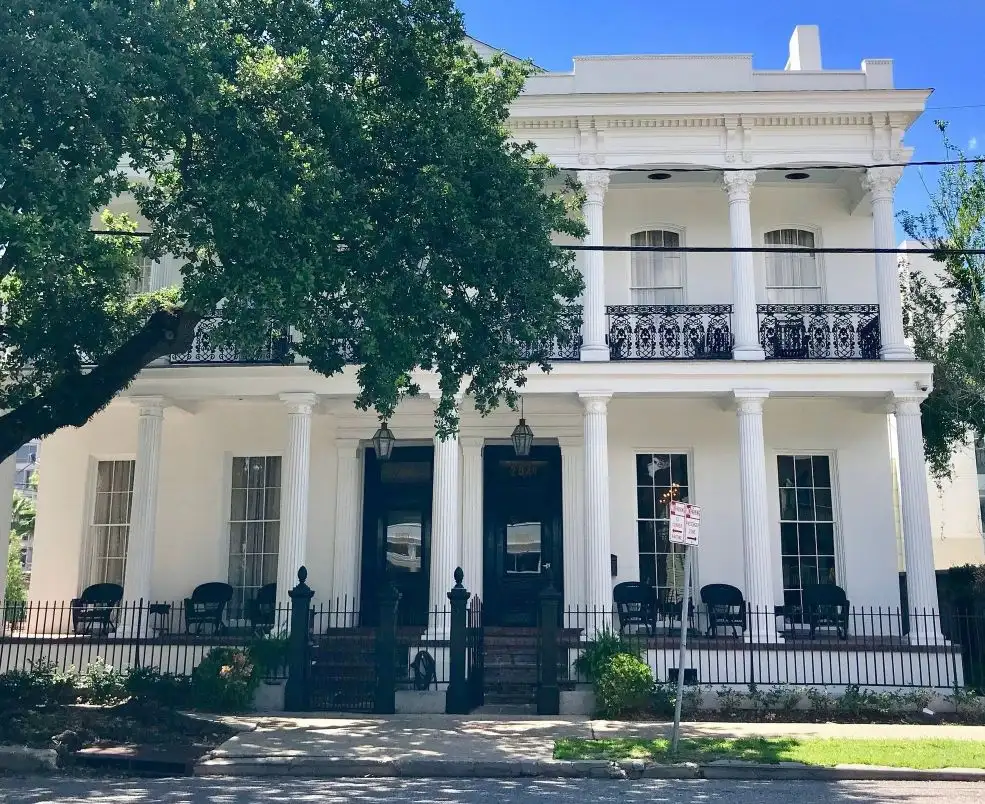 Exterior of the Henry Howard Hotel in New Orleans with Greek Revival columns and iron balconies