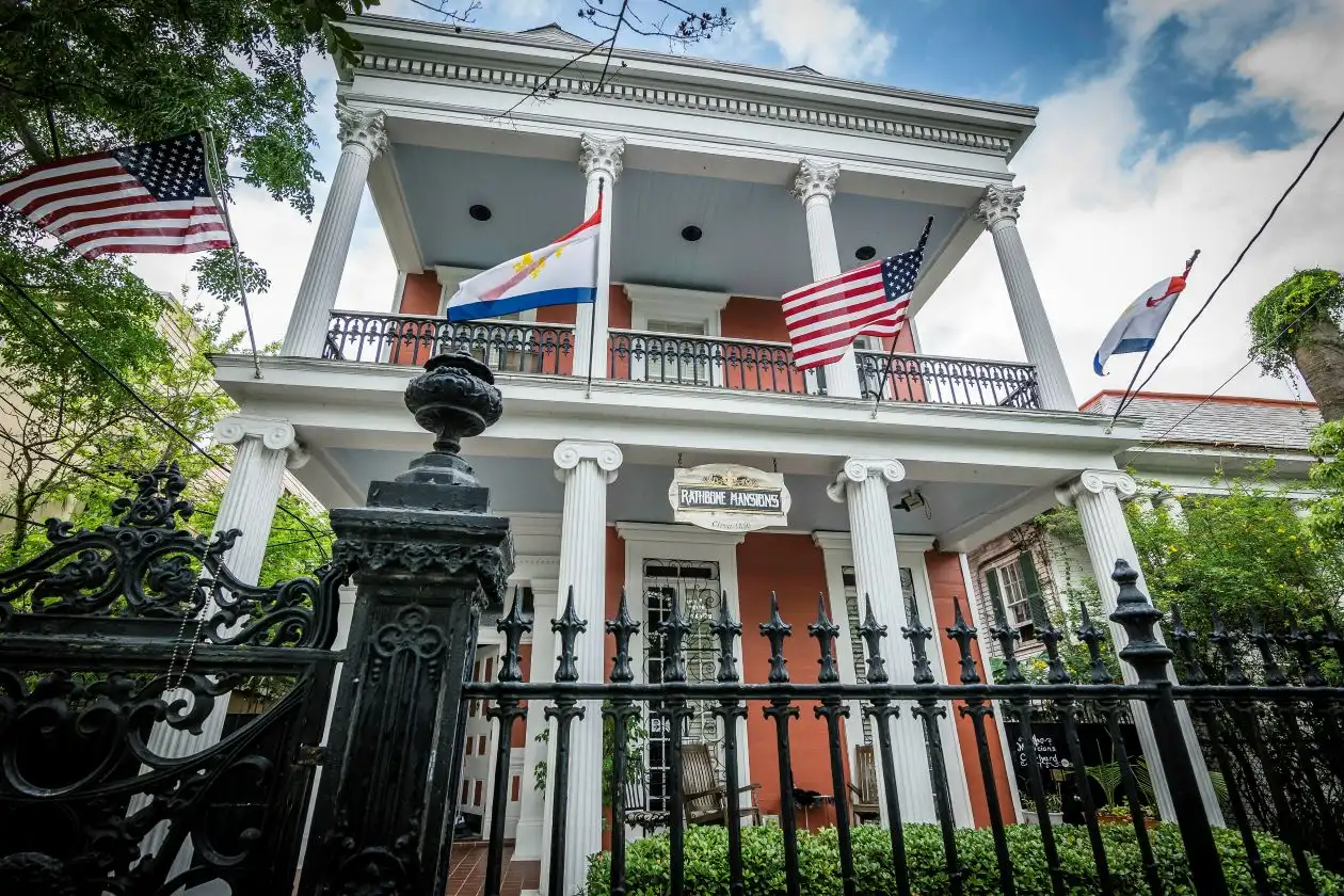 Exterior of Rathbone Mansions on Esplanade Avenue in New Orleans with flags and ornate iron fence