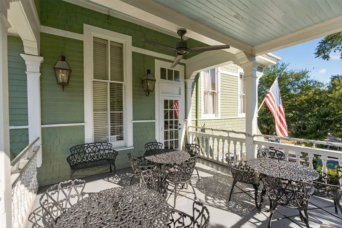 Wraparound shared balcony at Grand Victorian Bed & Breakfast with ornate iron furniture and gas lanterns overlooking St. Charles Avenue