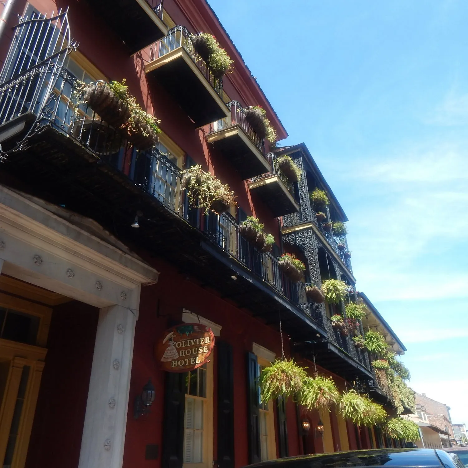 Olivier House Hotel exterior with wrought-iron balconies and hanging ferns in the French Quarter of New Orleans