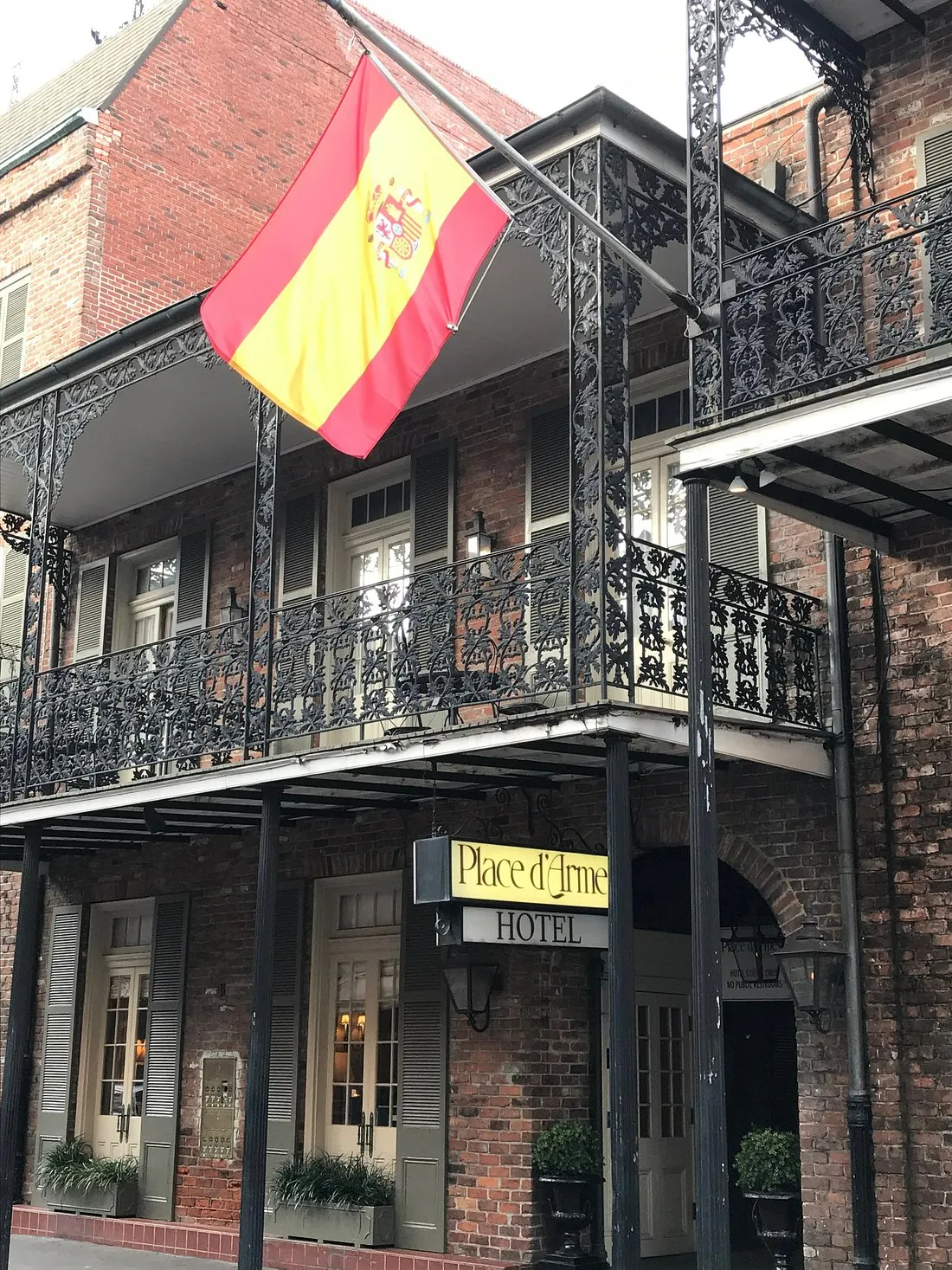Exterior of Place D'Armes Hotel showing ornate wrought-iron balconies above the entrance in the French Quarter